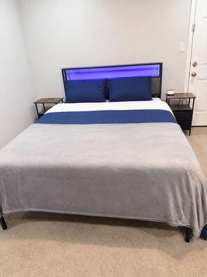 A bed with a headboard, a bedside table, and a nightstand. - Group Duplex near NRG with 7-Car Gated Parking (Houston)