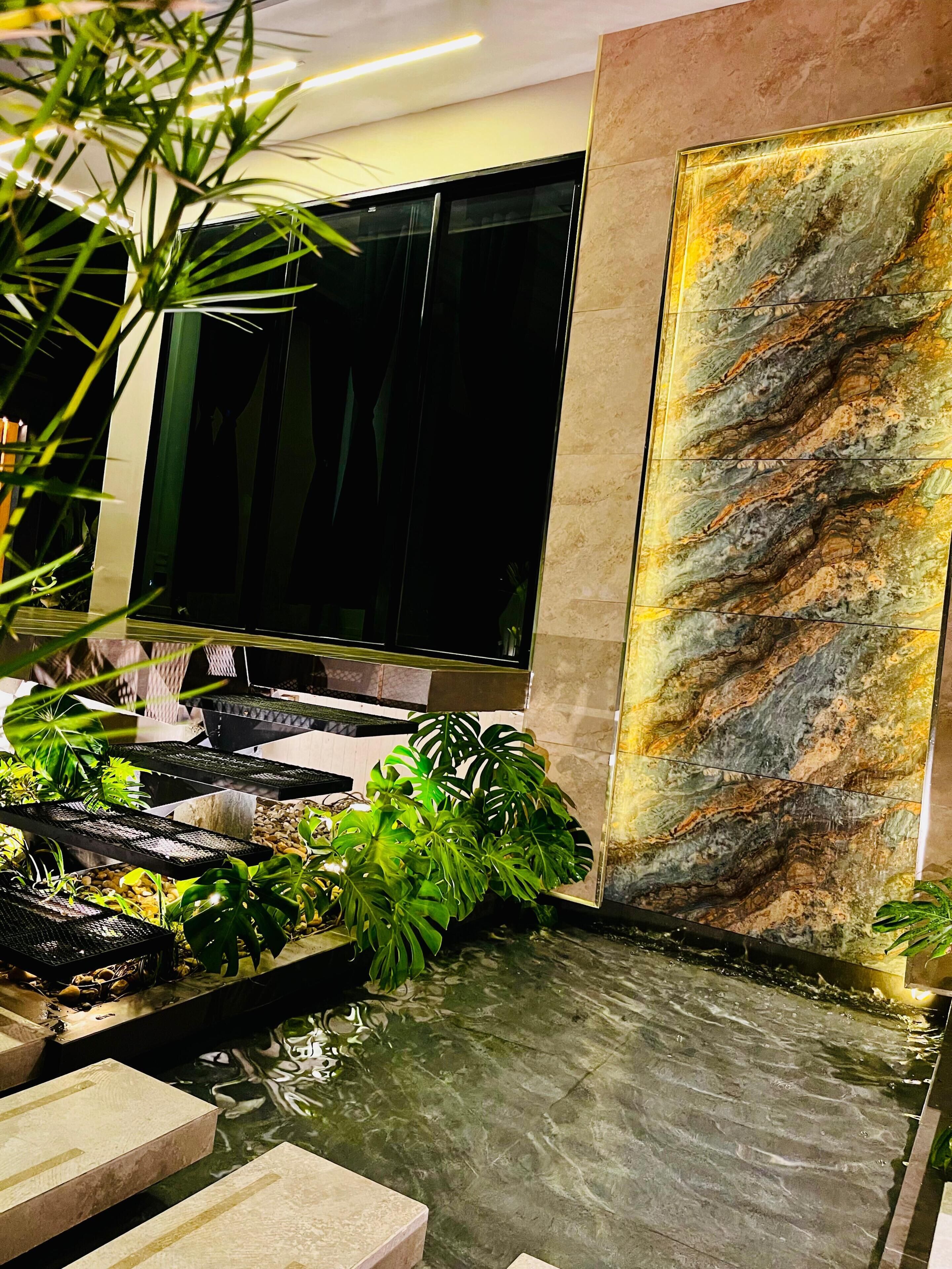 Een modern interieur met een waterattractie, een grote flatscreen televisie en een marmeren wand.