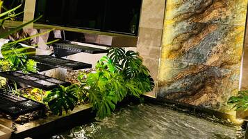 Een modern interieur met een waterattractie, een grote flatscreen televisie en een marmeren wand.