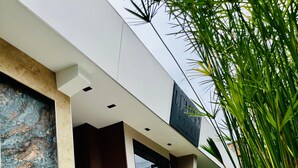 A modern hotel with a stone facade, a large potted plant, and a staircase leading to the entrance. - Lumina Hotel Elegancia y confort (Armenia)