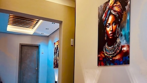 A hotel hallway with a marble floor, a painting on the wall, and a door with a number sign. - Lumina Hotel Elegancia y confort (Armenia)