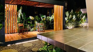 An outdoor patio area with a wooden deck, seating, and lush greenery. - Lumina Hotel Elegancia y confort (Armenia)