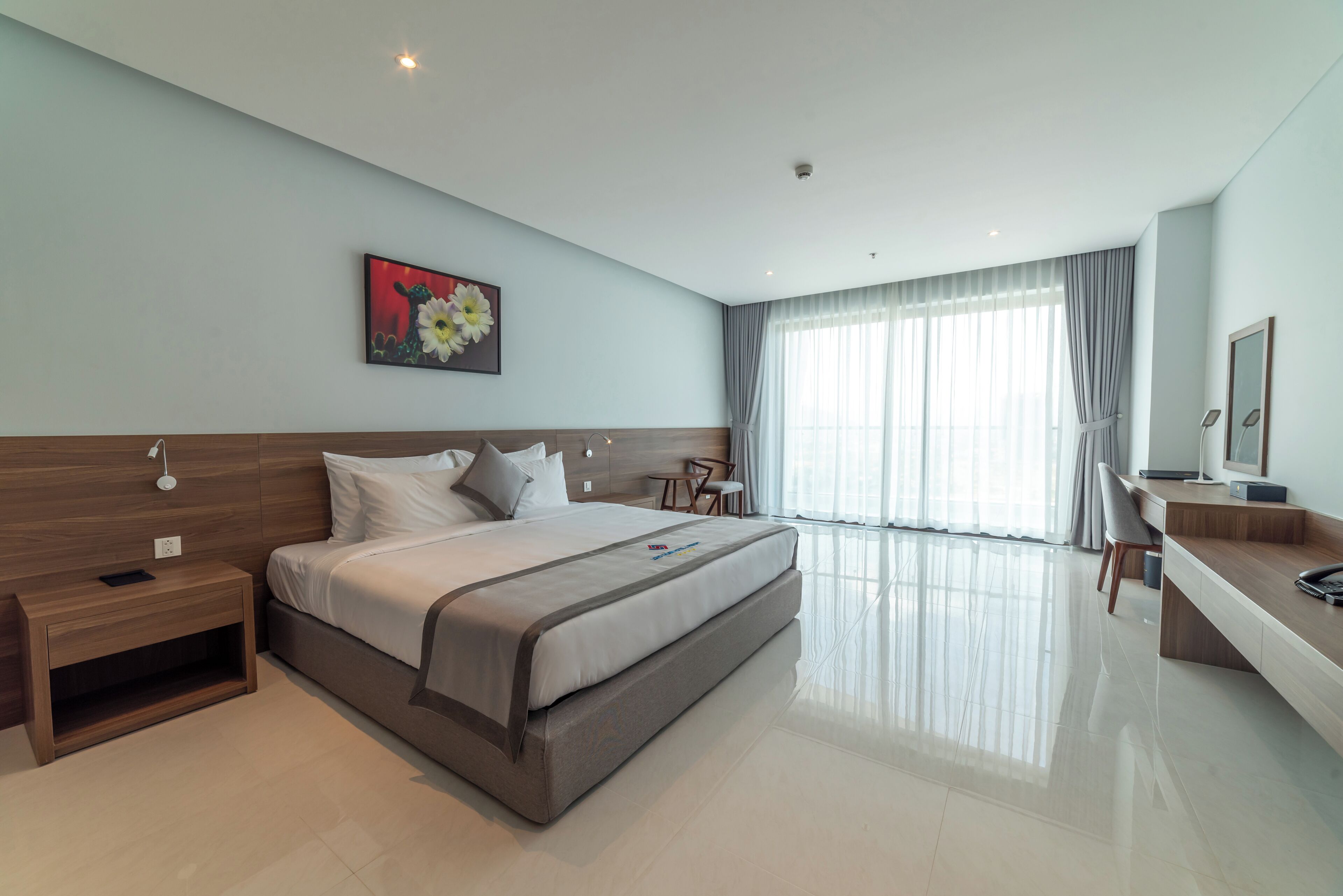 A modern hotel room with a large bed, bedside tables, a desk, and a chair.