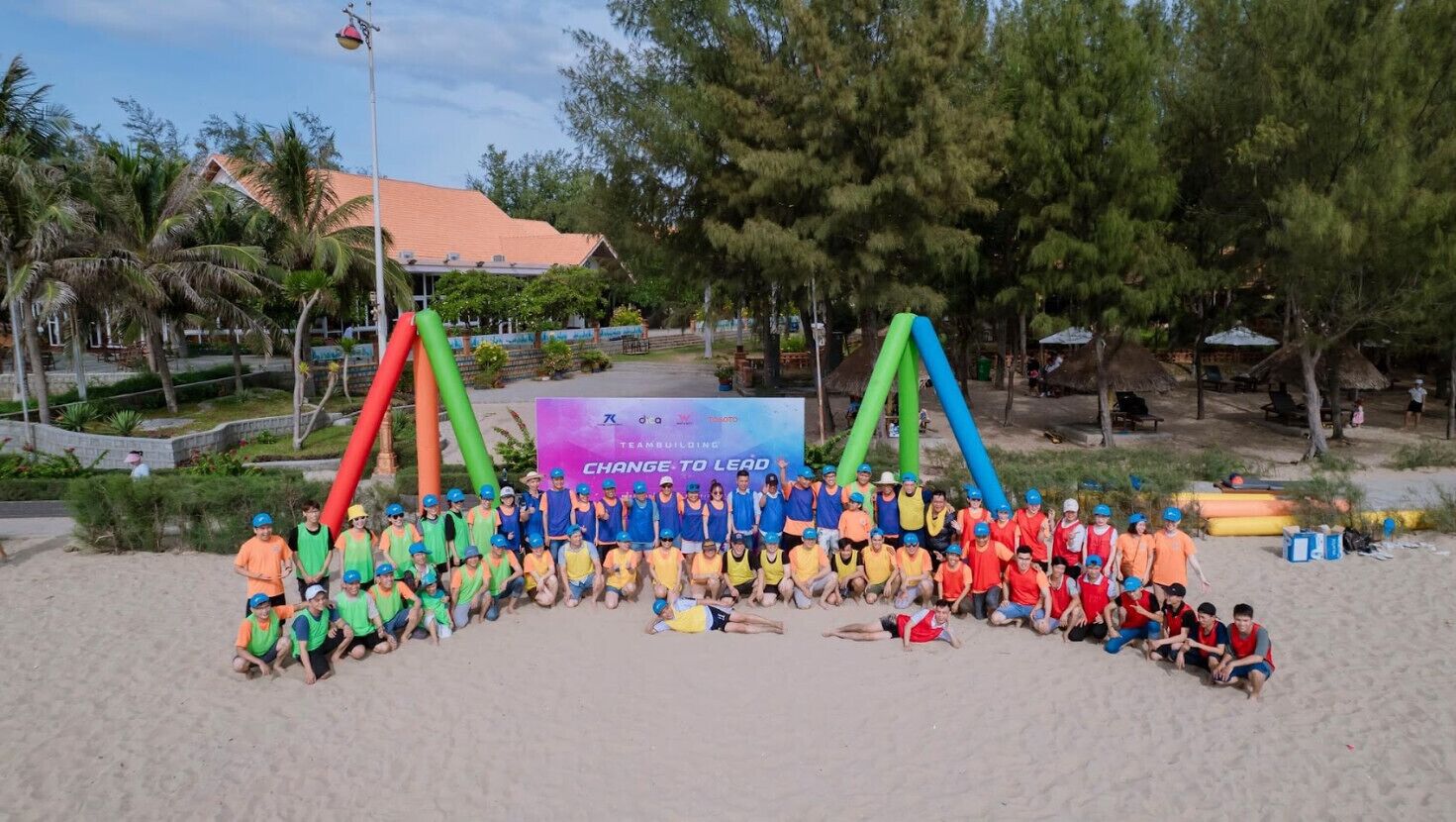 Een groep mensen op een strand, met een spandoek op de achtergrond.