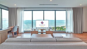 A modern hotel room with a large window, a flat-screen TV, a wooden desk, and a sofa. - Long Thuan Hotel & Resort (Dong Hai)