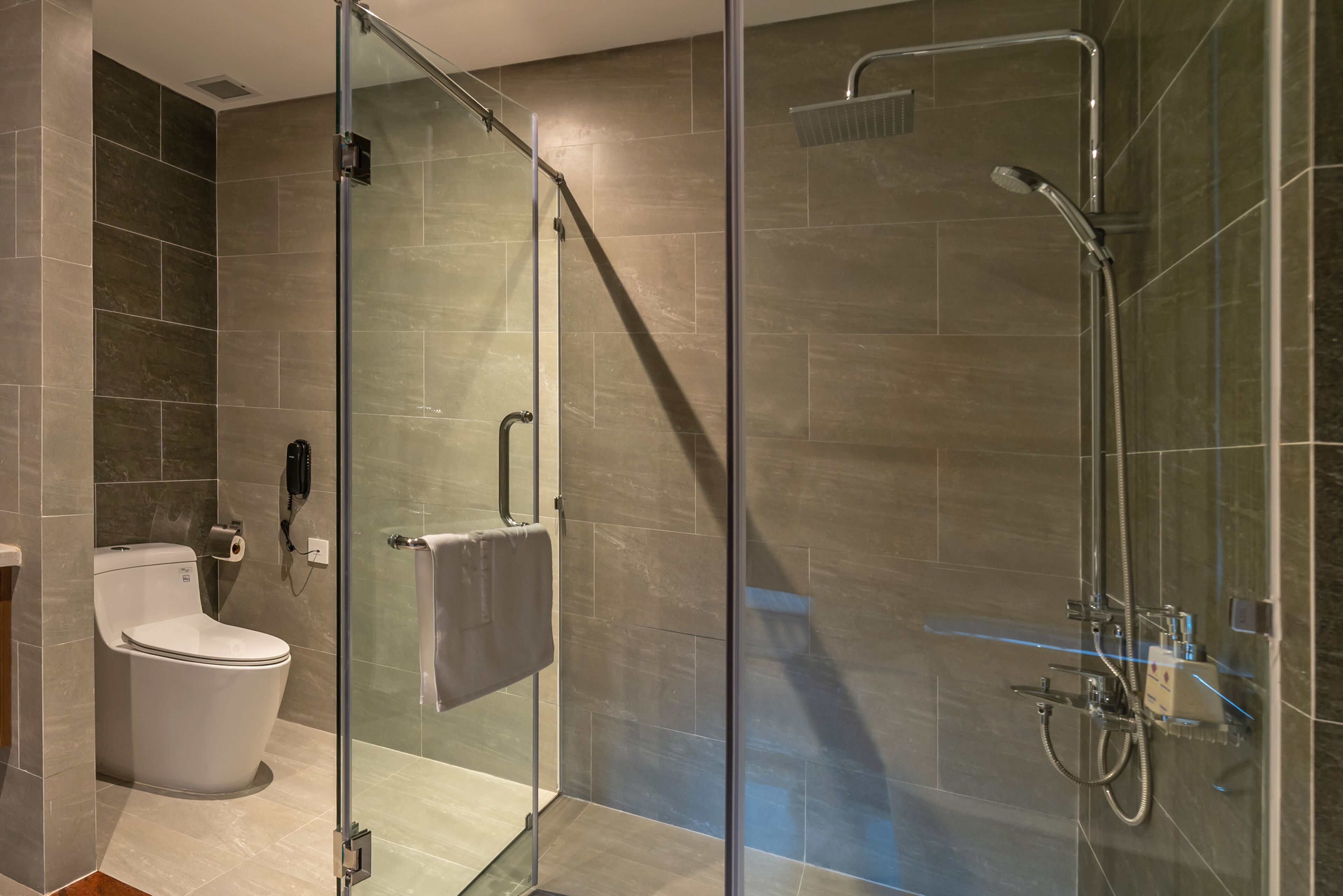 Un baño moderno con cabina de ducha de vidrio, un inodoro y un perchero para toallas.