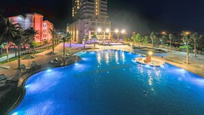 A nighttime swimming pool area with a large building in the background. - Long Thuan Hotel & Resort (Dong Hai)