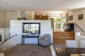 Ein modernes Wohnzimmer mit Treppe, Essbereich und Küchenzeile.