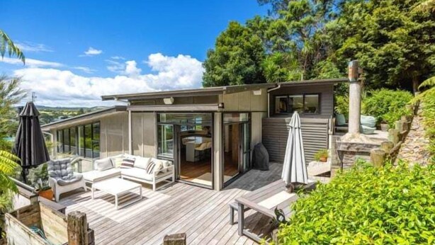 A modern house with a deck, outdoor seating, and a view of the surrounding greenery. - Huruhi Bay Retreat by Waiheke Pure - Views, stylish, spacious and central (Waiheke Island)