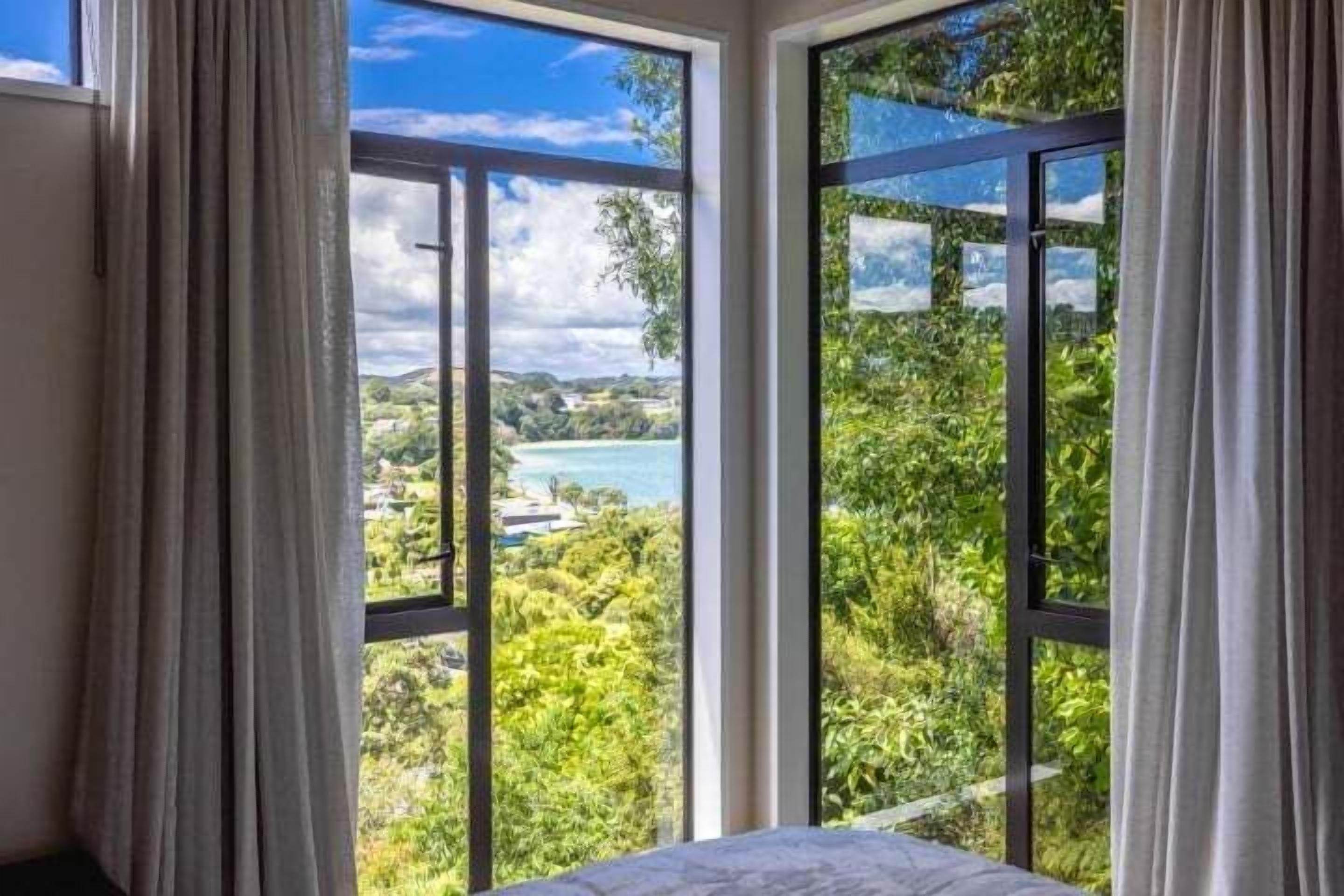 A room with large windows offering a view of a lake and greenery.
