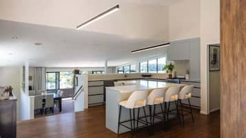 A modern kitchen with a central island, bar stools, and a dining area with a table and chairs.