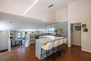Une cuisine moderne dotée d’un îlot central, d’un coin repas avec des chaises et d’un escalier menant à un niveau supérieur.