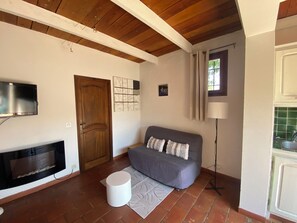 Un soggiorno con TV, camino, divano e lampada.
