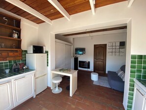 Una cucina compatta con un forno a microonde, un tavolino e uno sgabello.