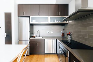 Eine moderne Küche mit Edelstahlgeräten, Holzschränken und einer schwarzen Arbeitsplatte.