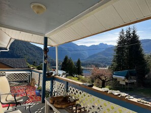 A covered outdoor area with a view of mountains and a lake.