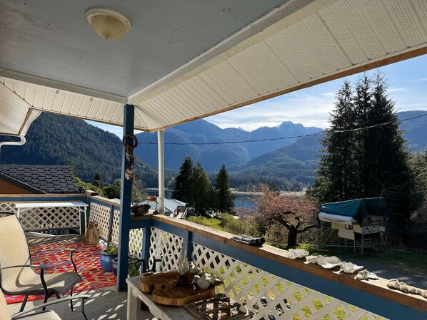 A covered outdoor area with a view of mountains and a lake.
