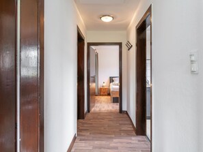 Ein Flur mit Holzboden, der zu einem Schlafzimmer mit Bett und Nachttisch führt.