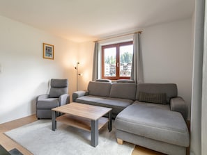 Una sala de estar moderna con un sofá gris, un sillón gris y una mesa de centro de madera.