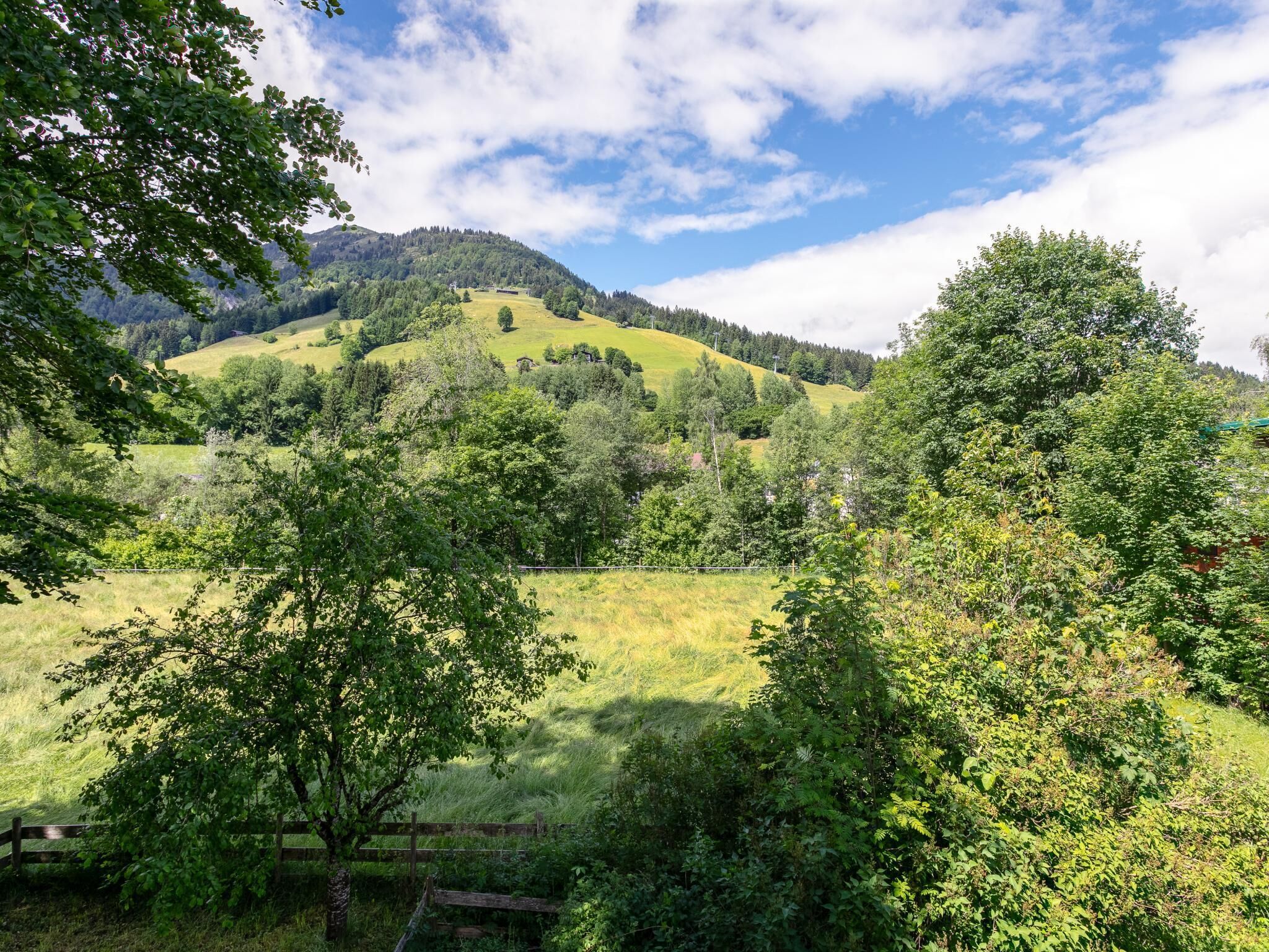 A rural landscape with rolling hills, dense greenery, and a clear sky.