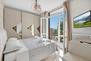 A bedroom with a bed, a TV, a window with a view, and a door leading to an outdoor area.