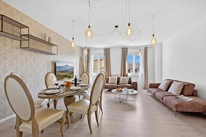 Un salon moderne comprenant un coin repas, un canapé et un lustre.