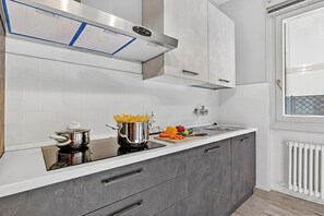 A modern kitchen with a built-in stove, a range hood, and a window with a view.