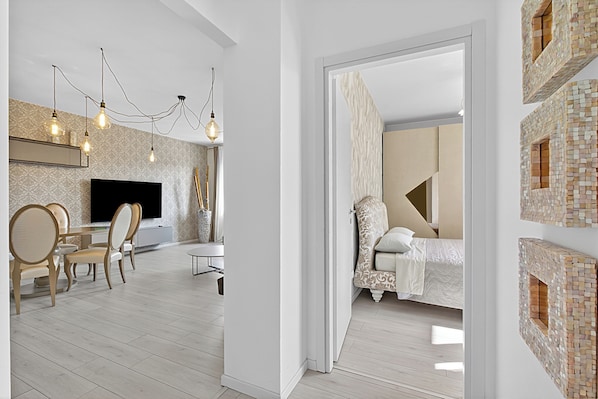 A modern interior with a dining area, a flat-screen TV, and a bed with a patterned headboard.