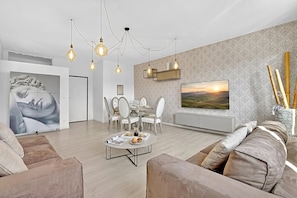 Un salon moderne comprenant un coin repas, un canapé, une table basse et un téléviseur fixé au mur.