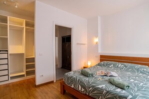A bedroom with a bed, a nightstand, a reading lamp, a wardrobe, and a closet. - Franklin's House Como (Como)