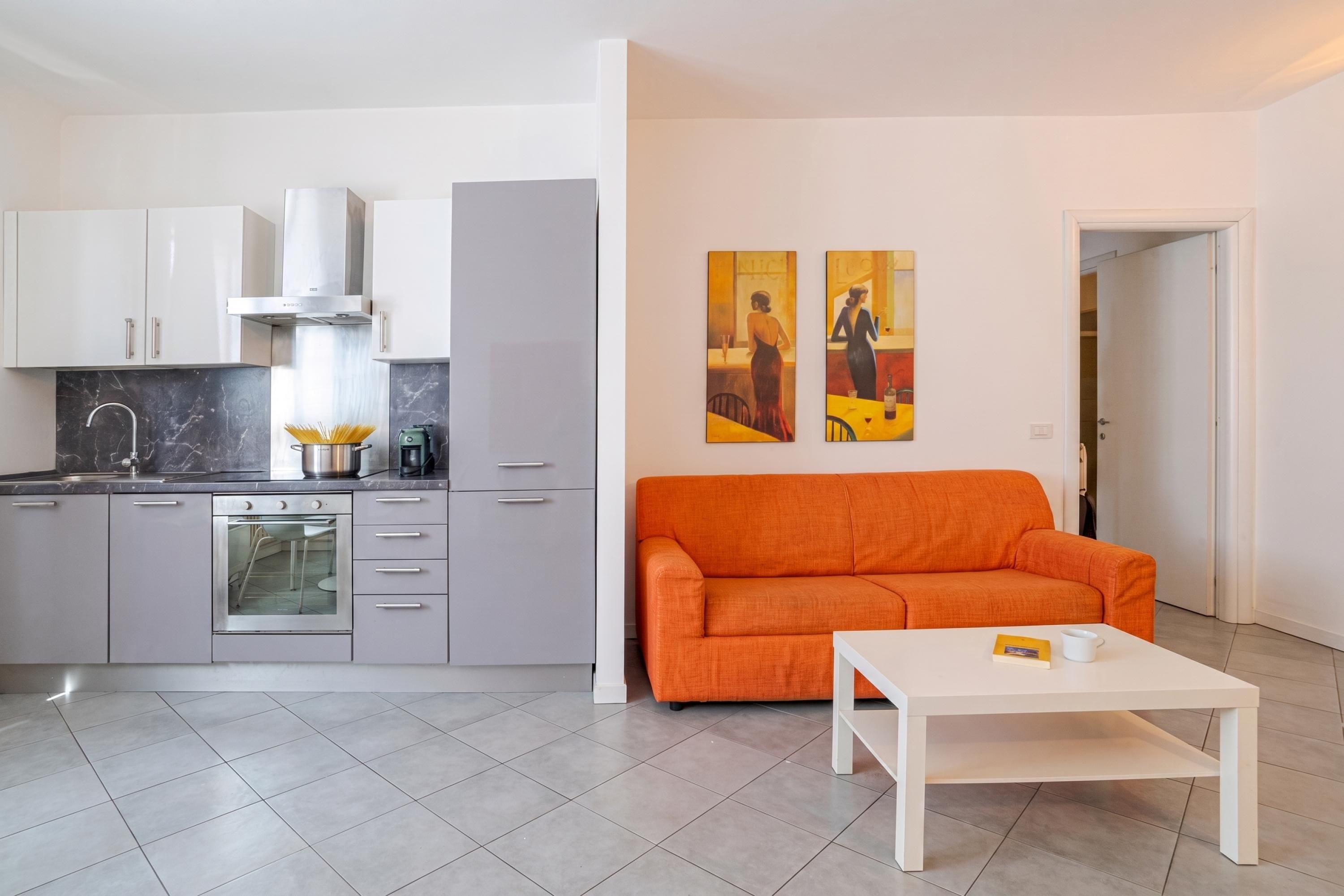 A modern kitchen with grey cabinets, a stainless steel range hood, and a built-in oven.