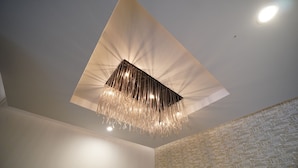 Teto moderno com luminária geométrica e parede texturizada.