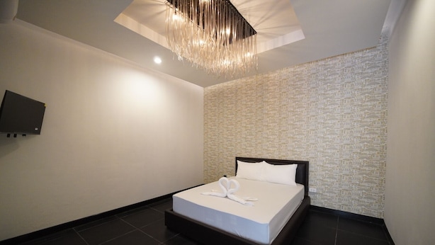 Quarto de hotel moderno com uma cama grande, televisão de tela plana na parede e luminária de teto com design exclusivo.