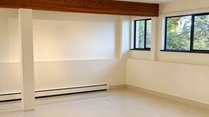 A spacious room with a high ceiling, large windows, and a central heating system. - One bedroom with bathroom (West Vancouver)