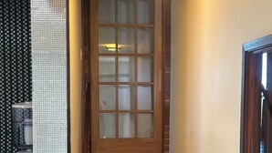 A staircase leading to a room with a wooden door, a water dispenser, and a tiled wall. - One bedroom with bathroom (West Vancouver)