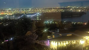 A nighttime cityscape with a prominent bridge and a building with illuminated windows. - One bedroom with bathroom (West Vancouver)