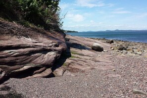 A rocky shoreline with a pebble beach and a large rock formation.