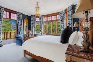 A bedroom with a large bed, a chandelier, a view of the outdoors, and a balcony. - Earnscleugh Castle (Alexandra)