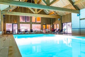Ein großer, überdachter Pool mit Holzbalken und gefliesten Wänden.