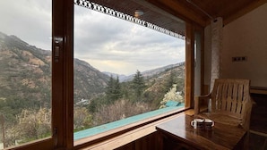 Una stanza con un tavolo in legno, una panca e un'ampia finestra che si affaccia su un paesaggio montuoso.
