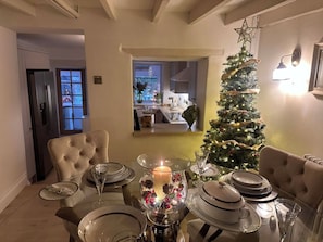 A dining area with a Christmas tree, a chandelier, and a view of the kitchen. - Rose Cottage, Cosy South Lake District Retreat, Sleeps 5 (Marton)