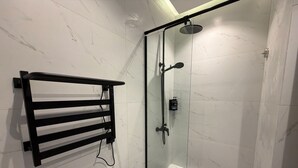 A glass-enclosed shower with a handheld showerhead, a black towel rack, and a small step leading into the shower. - 412 Tara-jre Jabal Al Lweibdeh With Stunning View (Amman)