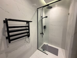 Eine Duschkabine mit Handbrause, einem schwarzen Handtuchhalter und einer kleinen Stufe zum Betreten der Dusche.