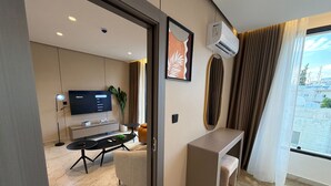 A modern hotel room with a flat-screen TV, a desk, a chair, a small table, and a potted plant. - 412 Tara-jre Jabal Al Lweibdeh With Stunning View (Amman)