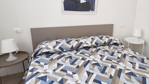 Habitació d'hotel amb un llit, dues taules de nit, una làmpada a cada taula i una obra d'art abstracta penjada a la paret.