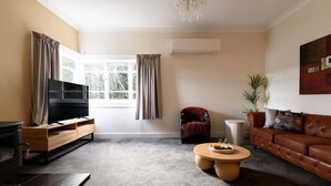 Ein Wohnzimmer mit Fernseher, Sofa, Couchtisch und Sessel.
