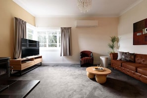 Ein Wohnzimmer mit Fernseher, Sofa, Couchtisch und Sessel.