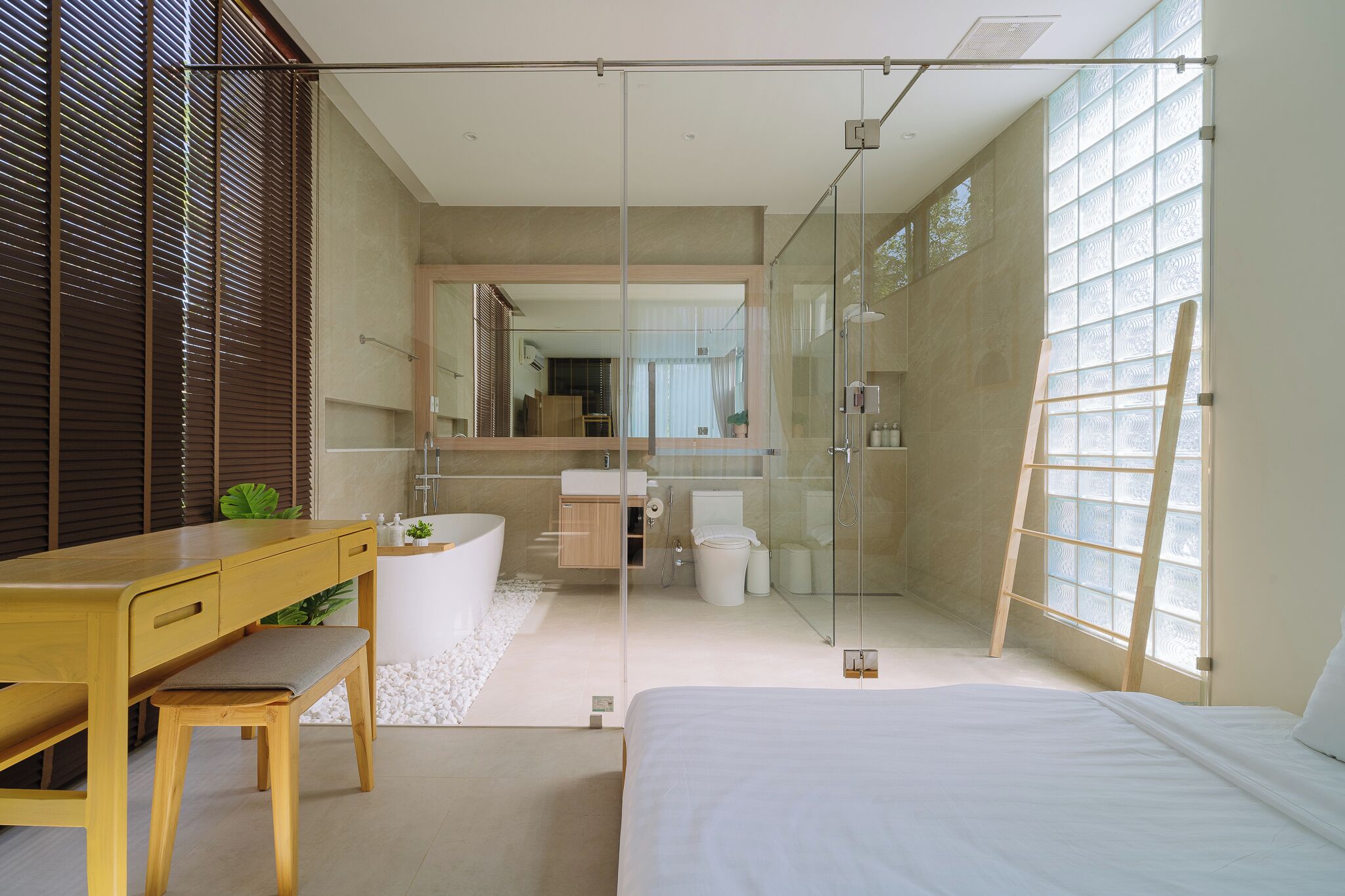 Un baño moderno con cabina de ducha de vidrio, un escritorio de madera y una cama grande.
