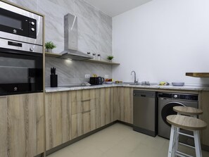 Eine moderne Küche mit Einbauofen, Mikrowelle und Geschirrspüler, Holzschränken und einer Marmor-Spritzschutzwand.