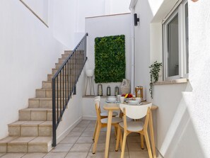 Eine Treppe führt zu einem Balkon mit Esstisch, einem Blumentopf und einem Fenster.